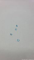 Four natural fancy Swiss blue topaz gemstones displayed on white background, showing their trillion cut shape and color.