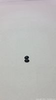 Two small untreated black opal gemstones on a plain white background, viewed from above.