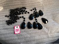 Photo of black glass teardrop prisms and beaded strands laid on a grey surface with a small auction tag.