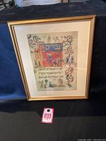 Framed Hebrew illuminated manuscript art showing a medieval city scene and Hebrew text with ornate border