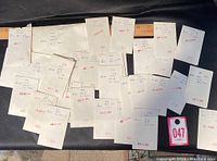 Photo showing 26 white envelopes each containing used Canadian stamps, arranged overlapping with handwritten catalog details and red date stamps.