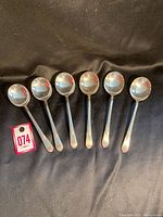 Photo showing six vintage soup spoons laid out on dark background