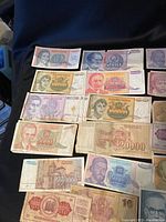 Overview of multiple Yugoslavian banknotes laid out on dark cloth background