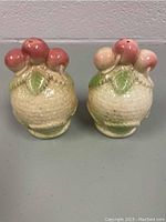 Pair of vintage ceramic salt and pepper shakers, basket-shaped with apples and leaves, shown front view.