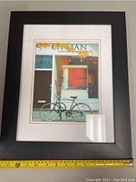 Framed artwork showing Paris storefront with bicycle and autumn leaves, approximately 17x14 inches.