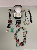 Full lot of costume jewellery including necklaces, earrings, rings, and a watch in a jewelry box.