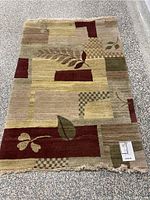 Full view of multi-color wool area rug showing leaf pattern and checkerboard blocks