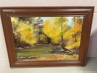 Framed landscape painting showing river and fall foliage