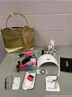 Photo of the full manicure lot displayed on a gray surface, including nail polishes, tools, wipes, and a gold tote bag
