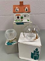 Three Party Lite candle holders arranged together showing ceramic house, hobnail glass, and flower-shaped glass holder with original box