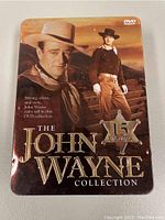 Front cover of the metal tin case for The John Wayne Collection showing 15 movie DVDs.