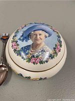 Photo of vintage commemorative dish lid featuring Queen Elizabeth The Queen Mother's portrait with floral wreath.