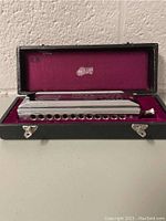 Harmonica in open case viewed from playing side showing holes and mouthpiece end.