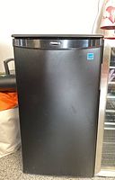 Front view of a matte black Danby bar fridge with logo and compact size.