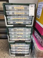Green storage units with multiple clear drawers labeled for various bead types and findings.