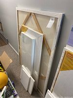Six blank canvases stacked against a wall showing various sizes including one large 36x48 inch canvas.