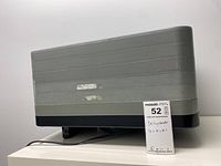 Side view of gray and black rectangular dehydrator showing power cord and sticker with dimensions