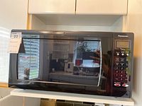 Microwave oven closed showing front black glass door and digital display panel on the right