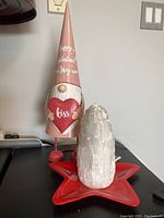 Metal Valentine themed gnome holding heart, white salt lamp, and red star plastic dish shown together.