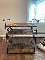 Front view of wicker shelf unit showing three woven shelves and metal frame