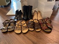Overview of all footwear including black ankle boots, moccasin-style shoes, sandals in tan, brown, and red, with eight plastic shoe boxes stacked nearby.