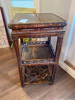 Full view of the 3-shelf wooden side table with carved details and signs of wear.