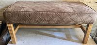 Photo of brown padded bench with stitched diamond design and wooden legs, showing bench top and side angle.