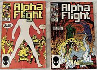 Photo of two Alpha Flight comic books, issue #25 and #24, placed side by side showing front covers with some wear and creases.