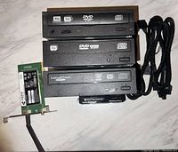 All items laid out showing three internal DVD drives and one WiFi antenna card with cable.