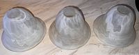 Photo of three glass light fixture shades with cloudy white swirl pattern placed side by side on a marble surface.