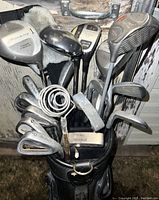 Close-up photo of golf clubs in black golf bag showing variety of club types including drivers and irons, with visible wear