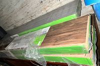 4 boxes of new hardwood flooring planks with green labels showing wood grain finish.