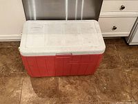 Front view showing red cooler body and textured white lid with Coleman logo.