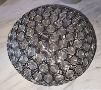 Top view of round domed light fixture with circular crystal elements held by silver-tone metal frame.