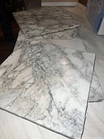 Photo of several 12x12 square marble tiles showing marble veining and used edges.