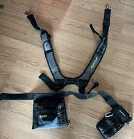 Photo of black WIP branded toolbelt with two adjustable straps, multiple pouches and metal hooks for fastening on straps.