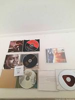 Top view of 5 CDs laid out with cases open showing front cover and discs, including Tracy Chapman albums and others.