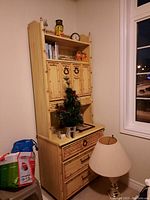 Full view of yellow bamboo hutch with visible three drawers, two cabinet doors, and open shelf area. Items on hutch are excluded from sale.