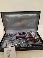 Opened carrying case showing 5 bar tools with wood handles inside satin lining.