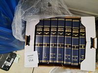Photo showing volumes 2 to 8 of Encyclopedia Americana encyclopedia, navy blue hardcovers with gold text.