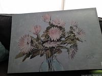 Floral painting on canvas showing pink flowers and green leaves in a vase, unframed, with a light gray background.