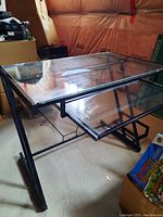 Glass desk showing the overall structure including the black metal frame and clear glass top surface.