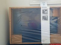 Photo of the IKEA Estetisk bulletin board still wrapped in plastic, showing wood frame and blue fabric area