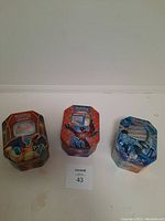 Three closed Pokémon card tins featuring Charizard, Mega Charizard X, and Kyurem artwork.