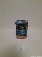 Three stacked Pokémon trading card tin cannisters showing front artwork.