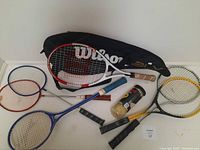 Image showing the full set of rackets including tennis, badminton, and squash rackets, tennis balls, and the black Wilson bag.
