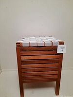 Front view of the teak wood storage container with white woven lid showing slatted wood sides and lid detail.