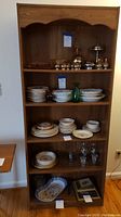 Tall bookcase showing multiple shelves with assorted dishes and decorative items.