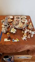 Image showing a table with porcelain figurines including horses, floral plates, and figurines including Disney characters and a large Hummel figurine.
