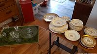 Full view of assorted porcelain plates, bowls, and glass serving items arranged on tables.